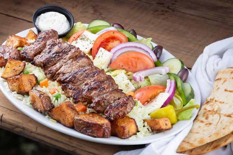 Steak souvlaki family meal platter with sides and Greek pitas